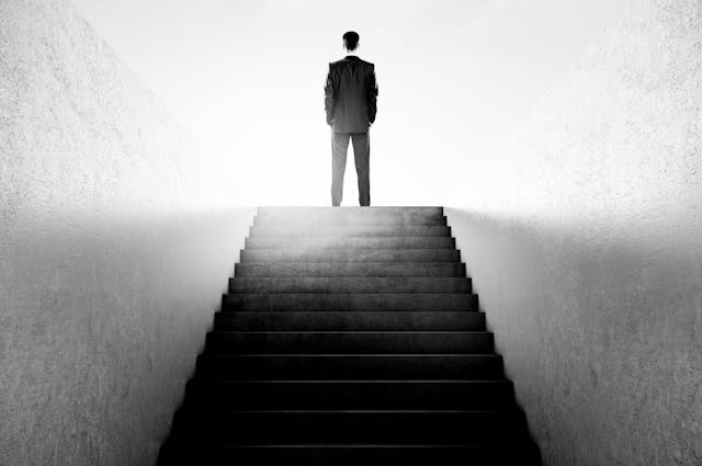 man standing facing away at top of stairs